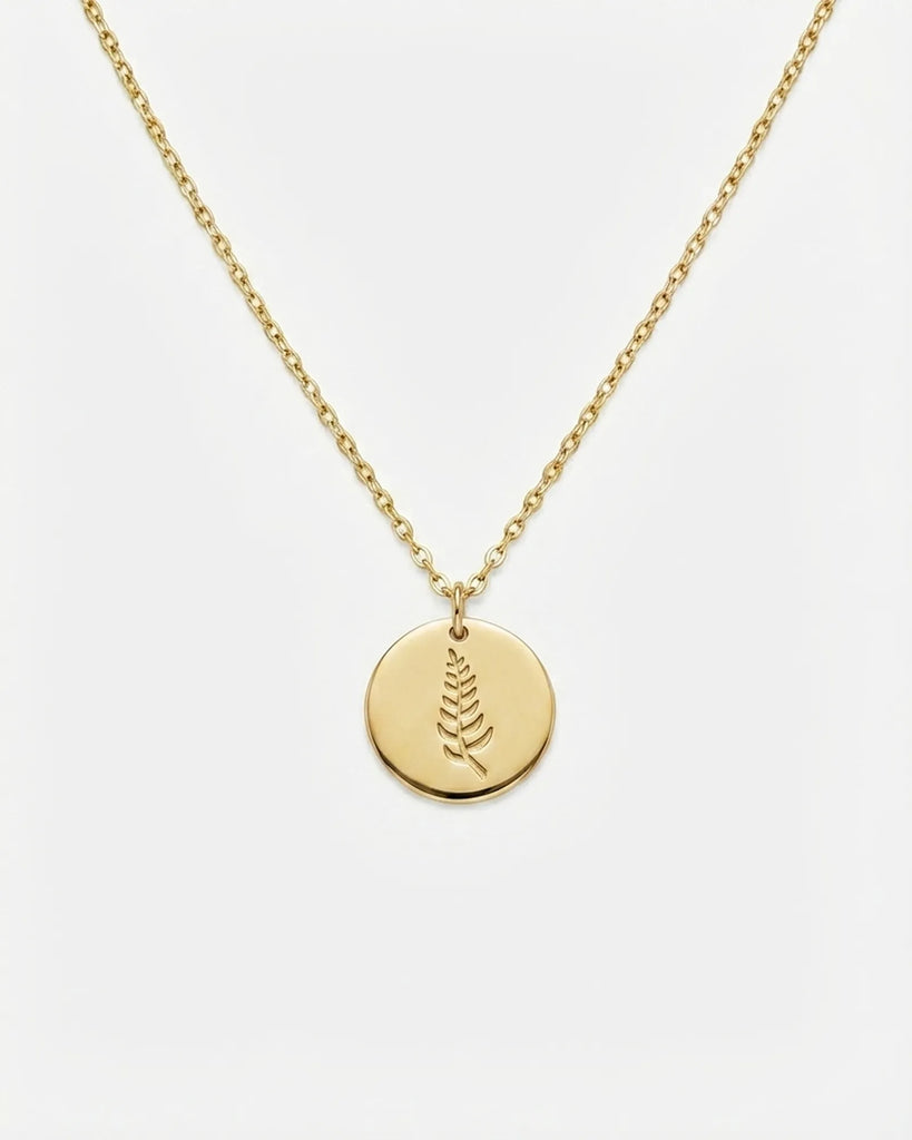 Gold necklace with a round pendant on a white background
