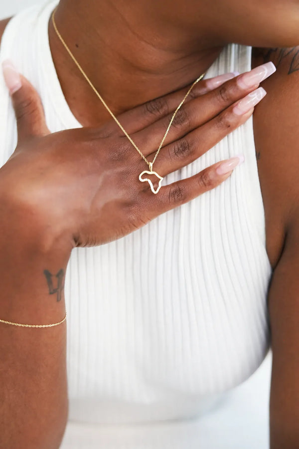 Gold necklace with a heart-shaped pendant worn by a person against a white background