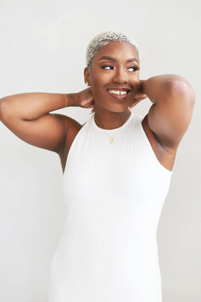 Woman wearing a white halter neck dress against a plain background
