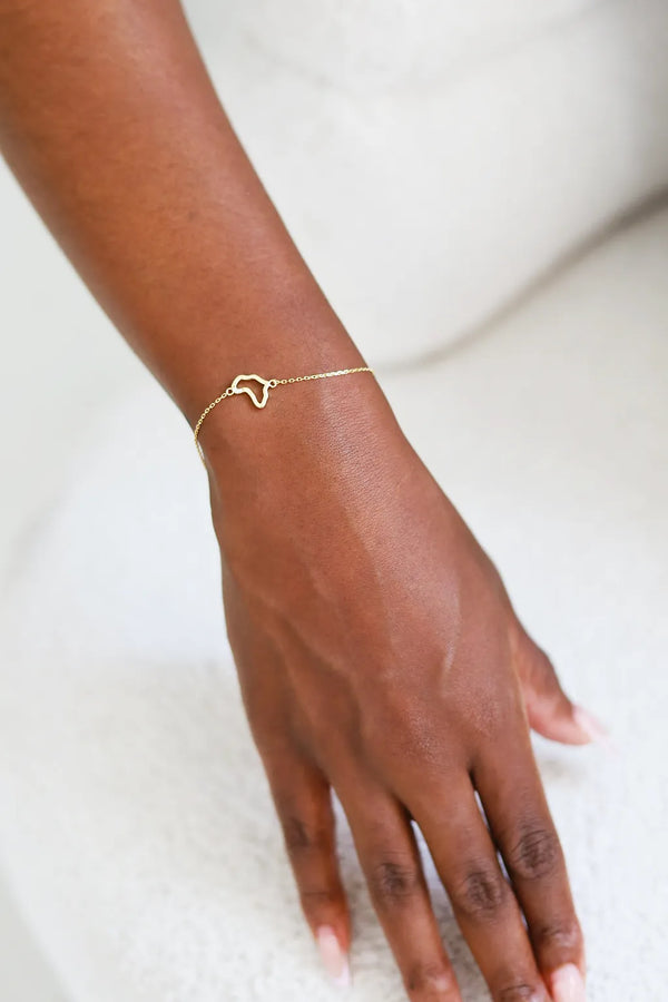 Gold bracelet on a person's wrist against a white background