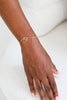 Gold bracelet on a person's wrist against a white background