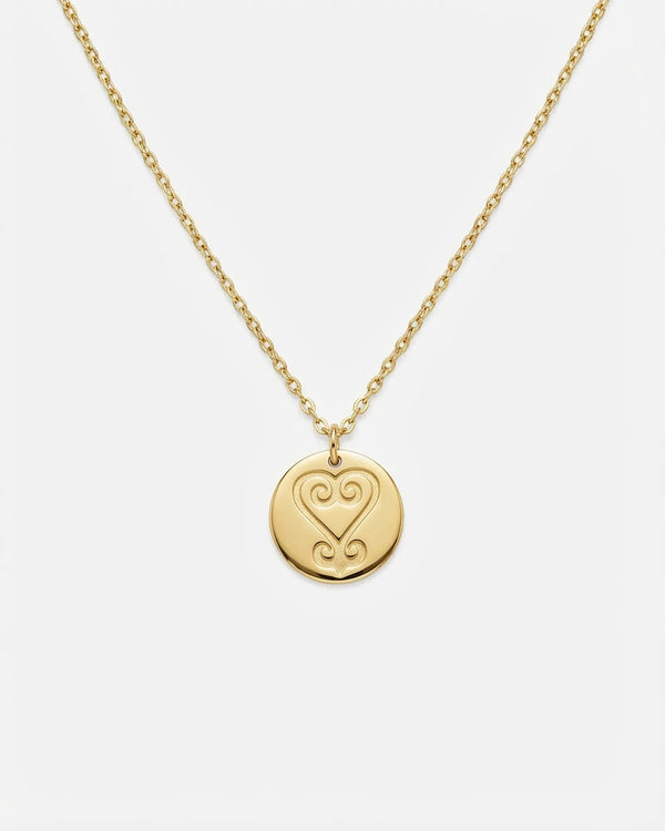 Gold necklace with a heart-shaped pendant on a white background