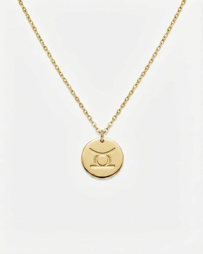Gold necklace with a round pendant on a white background
